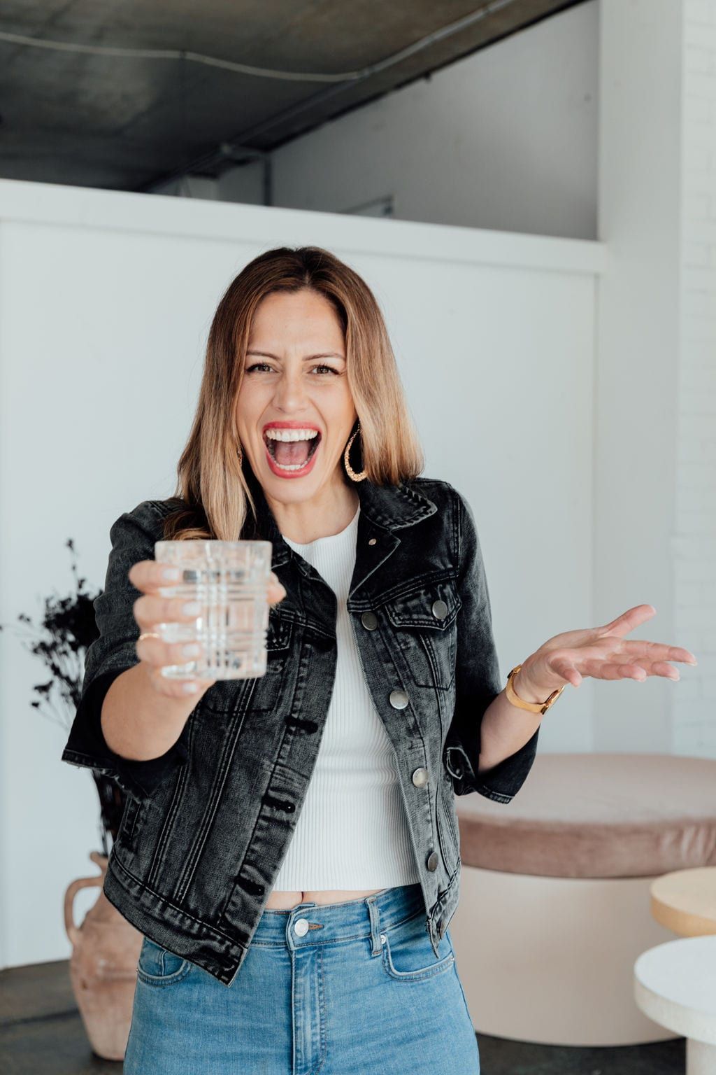 Dee Zibara laughing and holding out a glass of water