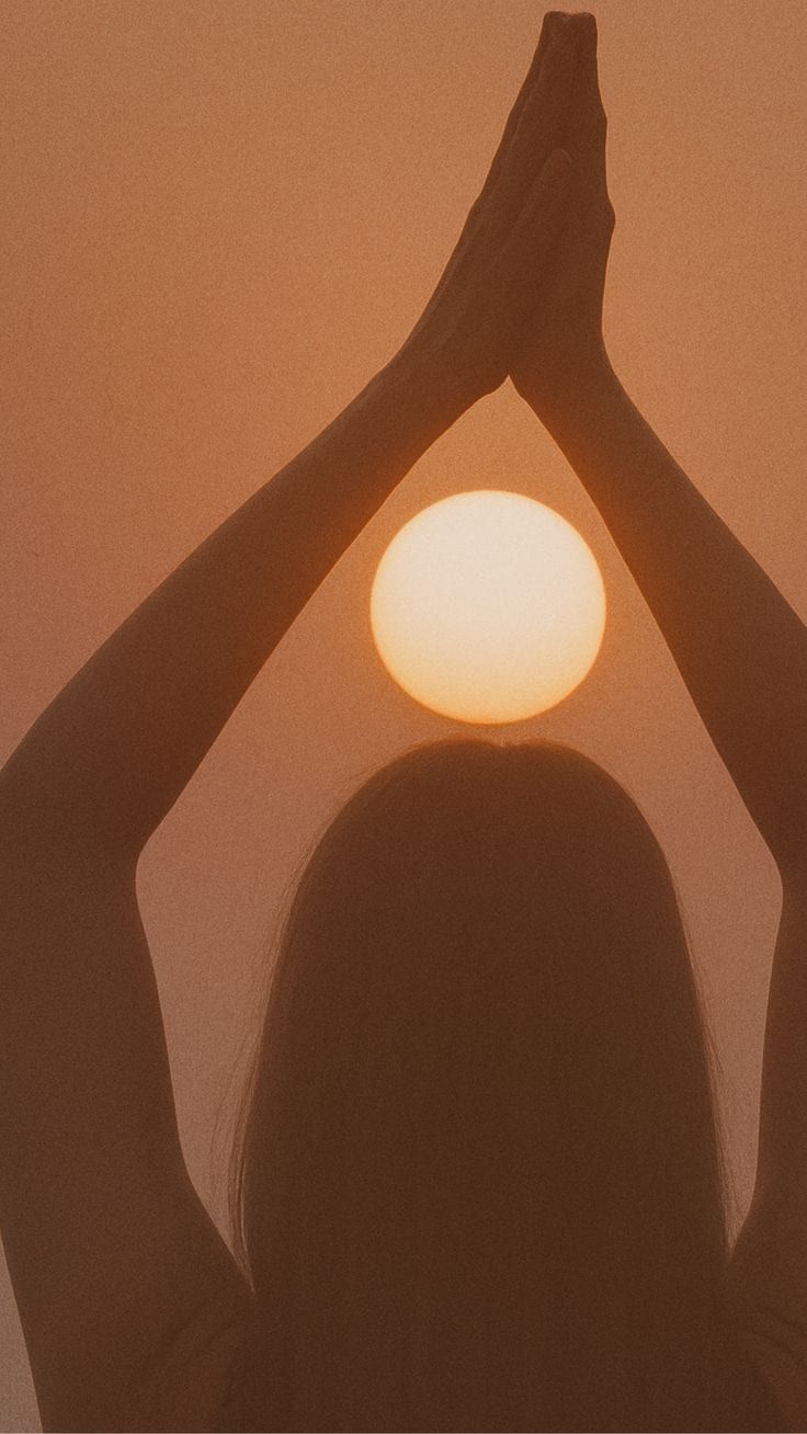 Silhouette of a woman with her hands raised above her head in front of the sun