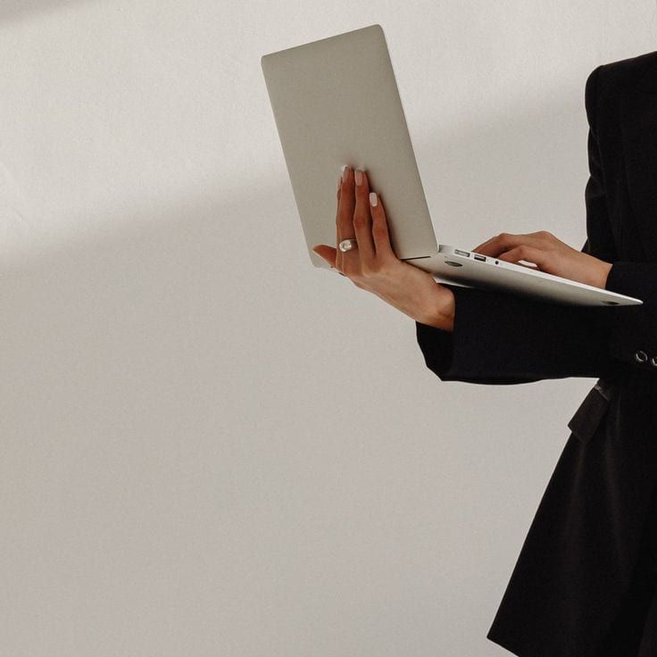 A woman in a black blazer holding an open laptop