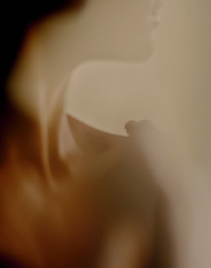 A soft, out-of-focus silhouette of a woman in warm light