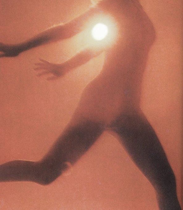 Blurred silhouette of a figure moving towards a bright light, in warm orange tones